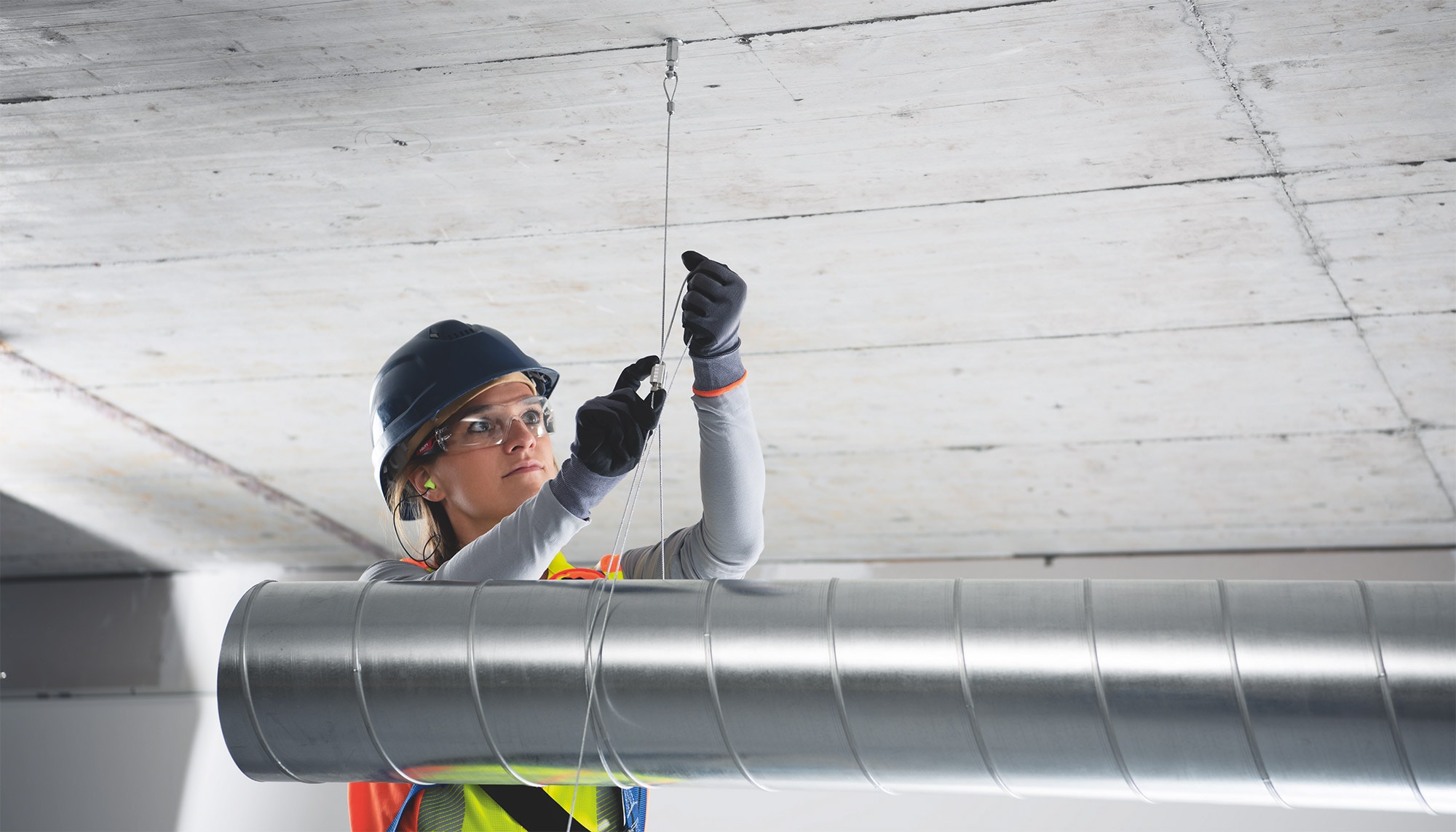 Een medewerker installeert een MW-ophangkabel ter ondersteuning van een leiding