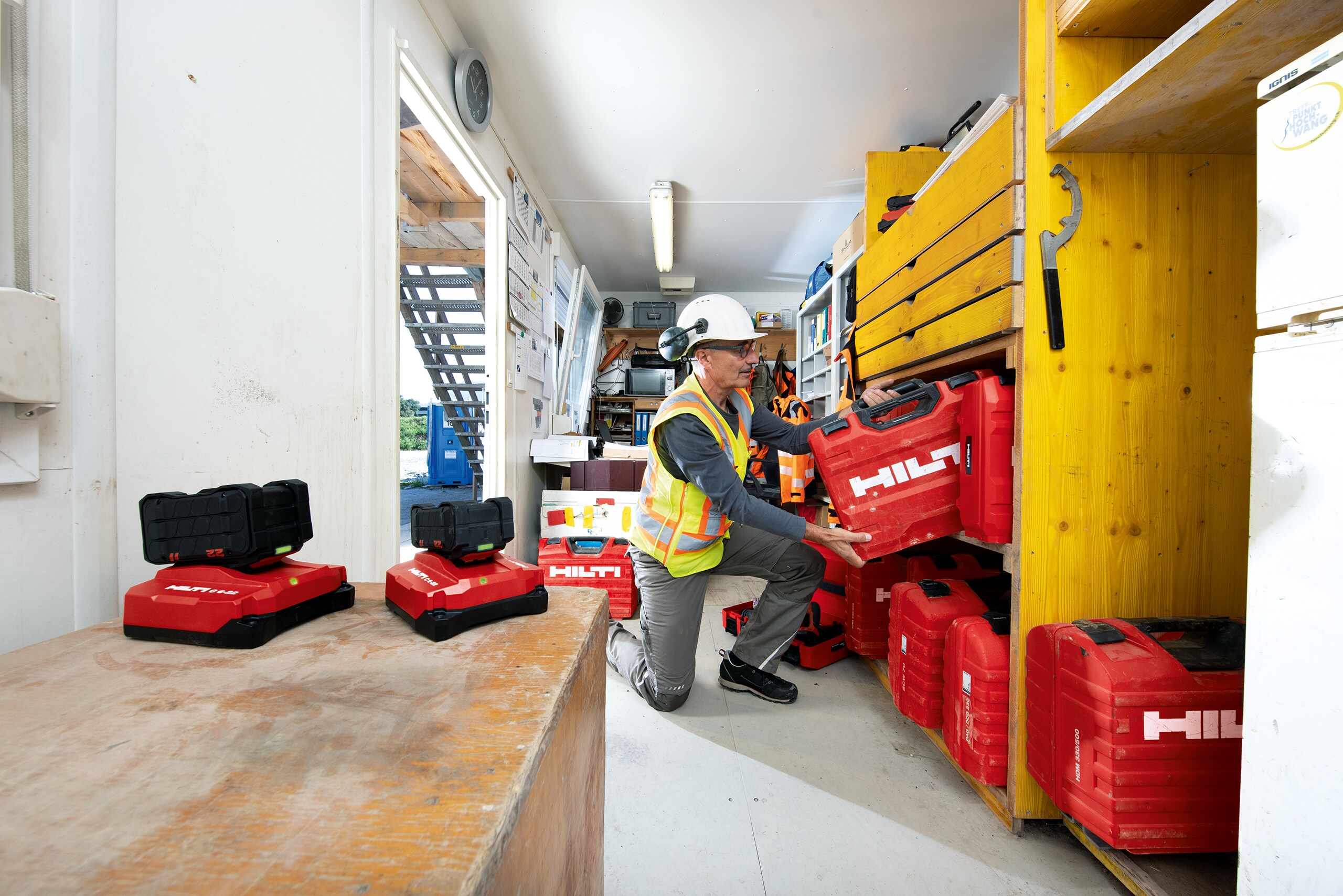 Een magazijnier legt een Hilti koffer op een rek in een werfcontainer