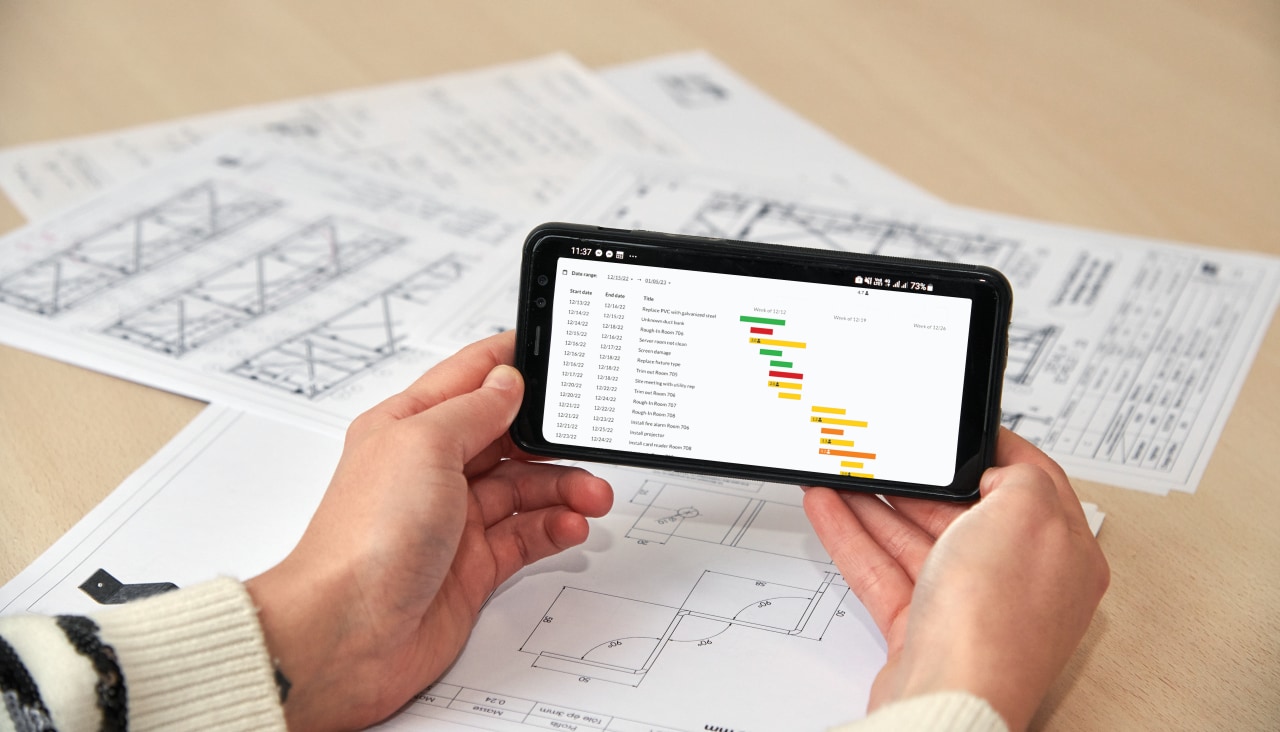 Deux hommes utilise l'application Fieldwire by Hilti depuis son mobile pour suivre l'avancée du chantier