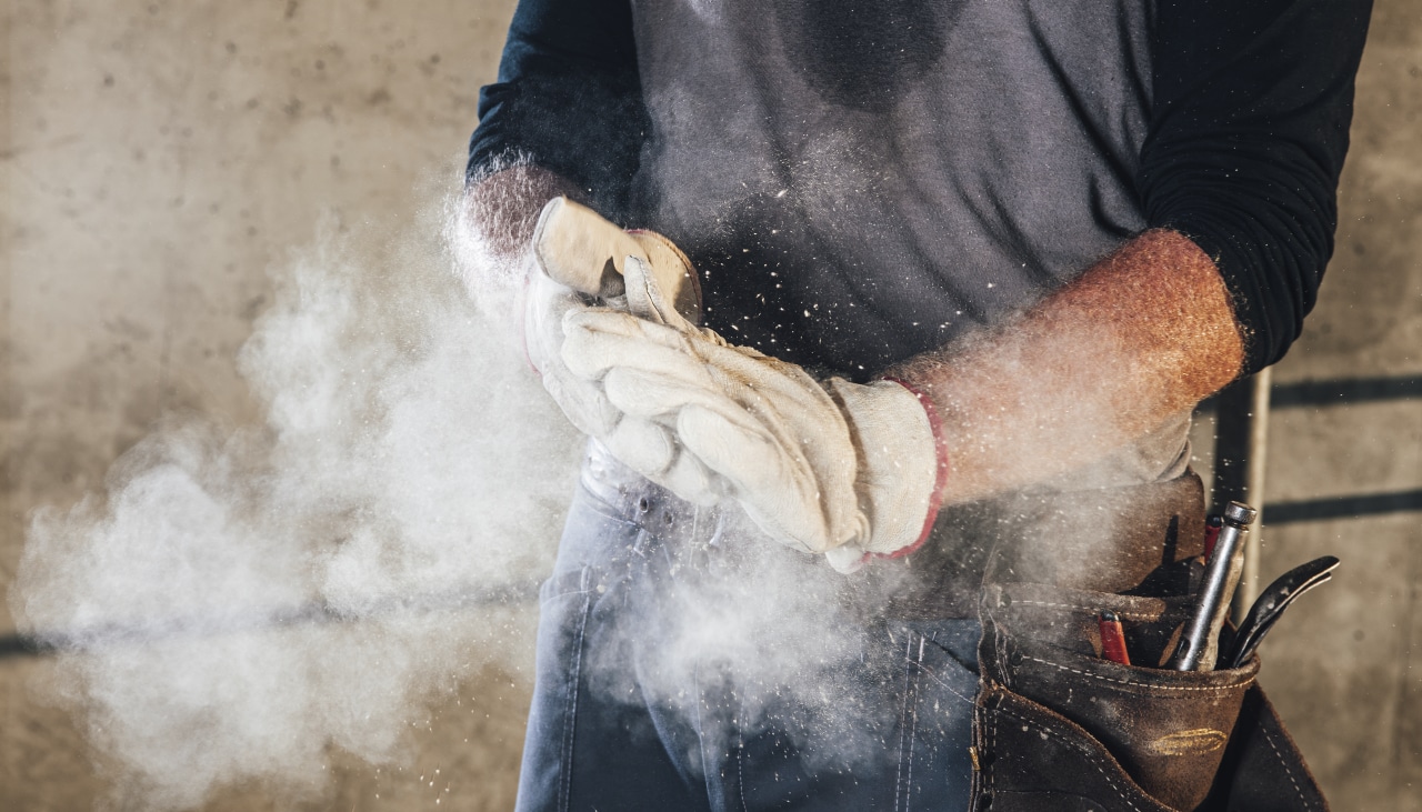 Ouvrier tapant ses gants de travail pour enlever la poussière de chantier