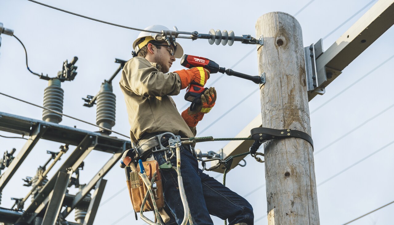 Bevestiging van kabels aan een elektriciteitspaal met een draadloze slagsleutel